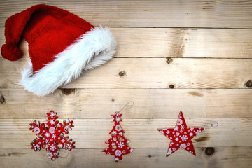 Obraz na płótnie Canvas santa hat with christmas decoration on a plank 