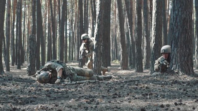 Slow-motion shooting as a soldier pulls a wounded comrade from under fire