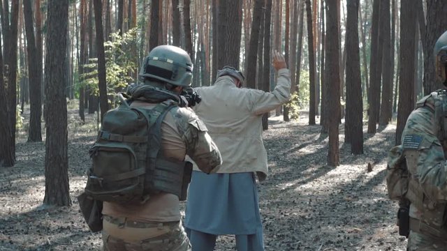 Slow motion of soldiers capturing Mujahideen man in forest