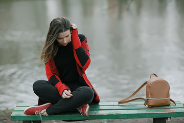 girl bench pond autumn / concept lonely girl in autumn relaxes near a pond on a garden bench, autumn landscape