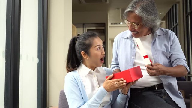 Couple of middle aged woman and senior man giving a surprise gift on her special day such as birthday or wedding anniversary. Celebration and holiday concept