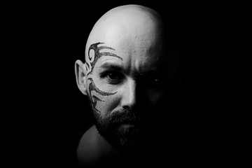 tattoo on the face,  man with a tattoo,  brutal bearded guy, studio portrait of a man