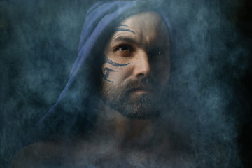 tattoo on the face,  male portrait in the form of an assassin, cosplay,  tattooed brutal man,  guy with a tattooed face
