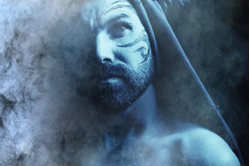 man's portrait in smoke, smoke from a hookah and a brutal guy. Unusual bearded man, portrait