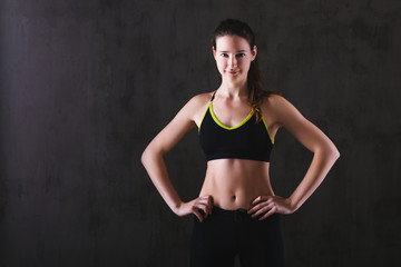 Fototapeta na wymiar Fitness woman training in dark studio. Young girl posing on black background