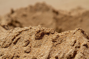 Mountain ranges of sea sand. Reduced model of mountains and rocks from sand. Canyons and cliffs created from sand. The concept of the desert and mountain ranges. Close-up.