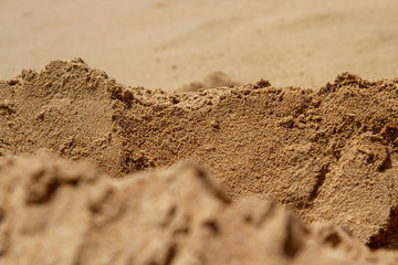 Mountain ranges of sea sand. Reduced model of mountains and rocks from sand. Canyons and cliffs created from sand. The concept of the desert and mountain ranges. Focus in the background.