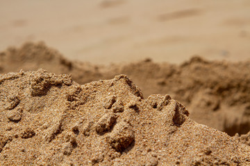 Mountain ranges of sea sand. Reduced model of mountains and rocks from sand. Canyons and cliffs created from sand. The concept of the desert and mountain ranges. With a free place in the background.