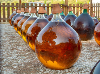 Making of natural sweet dessert muscat liqueur white wine outside in big round glass antique demijohn bottles in Frontignan, south of France © barmalini