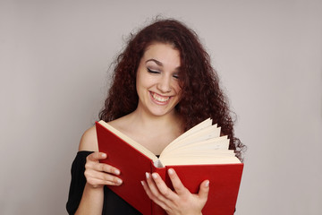 smiling teenage girl enjoys reading a funny hardcover book            