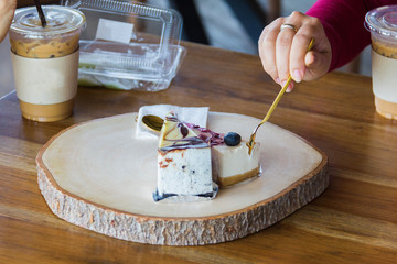 Woman use spoon to scoop blueberry cake from chopping block in cafe