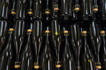 Bottiglie in vetro scuro con tappo in sughero e gabbietta in posizione orizzontale in una cantina vinicola © vpardi