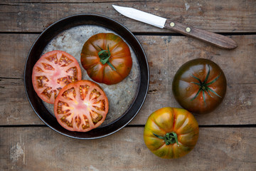 Reife farbige Tomaten zusammen mit einem Messer auf einem alten Holzuntergrund