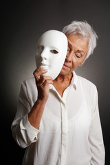 mature woman revaling sad face behind mask. depression concept.