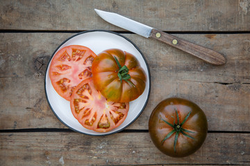 Reife rote Tomaten zusammen mit einem Messer auf einem alten Holzuntergrund