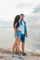 beautiful happy couple hugging on beach near sea