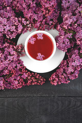 Cup of tea and branches of flowers bouquet blooming lilac