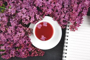 Cup of tea and branches of flowers bouquet blooming lilac