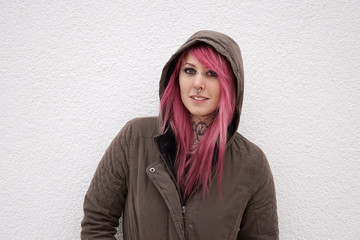 portrait of a young alternative woman with pink hair piercings and tattoos                         ...