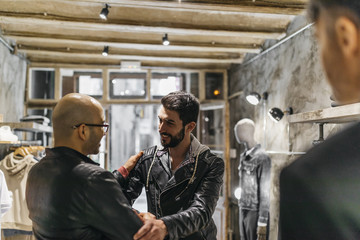 Obraz na płótnie Canvas Two smiling men meeting in modern menswear shop