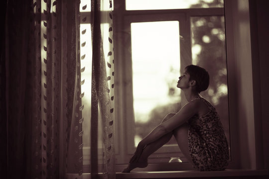 Silhouette Of A Dreamy Girl Sitting On A Window