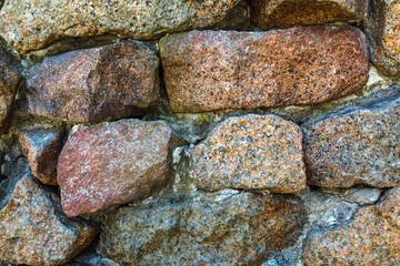 Ancient weathered wall constructed of natural cobblestone. Colorful horizontal image suitable for interior design, backdrop, wallpaper. Template background for advertising, products montage.