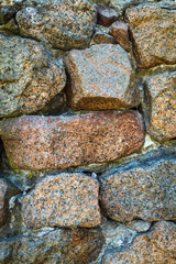 Ancient weathered wall constructed of natural cobblestone. Colorful horizontal image suitable for interior design, backdrop, wallpaper. Template background for advertising, products montage.
