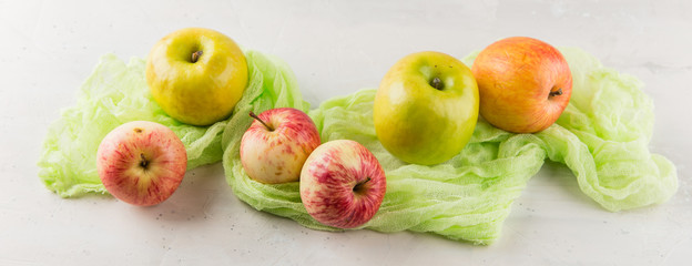 Green and red apples on a light background with a green cloth