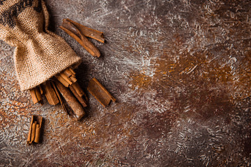 Cinnamon sticks in a canvas bag on grunge brown backround