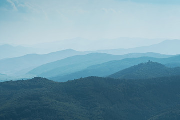 Obraz premium Abstract blue Landscape with Silhouettes of Misty Mountains and Forest. Multilevel Mountain Range in the Background and a Dense Forest in the Foreground