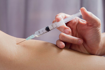 Hands of medical doctor with injector doing vaccination