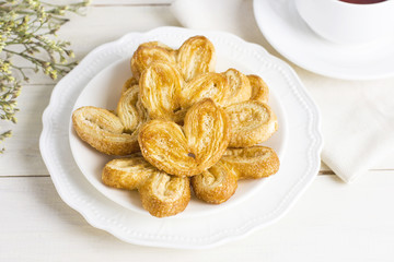 Puff pastry hearts on a white plate with a Cup of tea