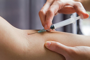 Hands of medical doctor with injector doing vaccination