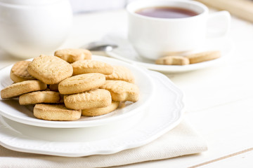 Fototapeta na wymiar Sugar shortbread cookies in white plate with cup of tea