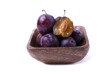 Fresh ripe blue plums in a wooden bowl. Isolated composition