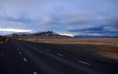 Cold winter morning on the road No. 1 in Iceland amid Mountains in snow caps and blue sky in dark clouds