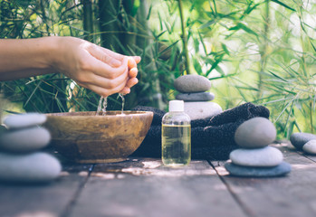  A woman's hand  and clear water  on an old wooden table. Japanese style. Simplicity, zen, relax, calm and peaceful mood. Copy space