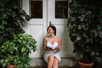 Gorgeous woman reading a book on a doorstep.