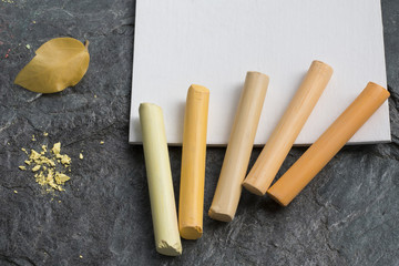 Pastel crayons in yellow colors, watercolor paper for drawing a leaf. Art supplies. Selective focus