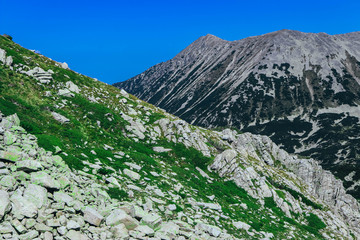 Beautiful alpine high mountains peaks, blue sky background. Amazing Mountain hiking paradise landscape, summertime.