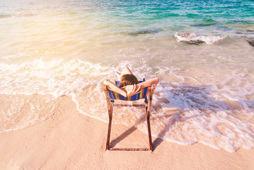 Fototapeta na wymiar Young lady relaxing in a chair on a beach at sunny day