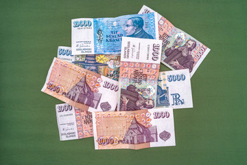 Pot of Icelandic krona banknotes laying on green carpet as a background
