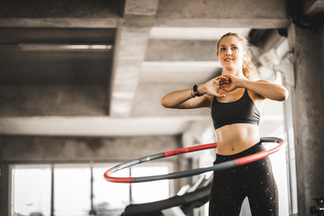 Beautiful caucasian young woman doing hula hoop in step waist hooping forward stance. Young woman doing hula hoop during an exercise class in a gym. Healthy sports lifestyle, Fitness, Healthy concept. - obrazy, fototapety, plakaty
