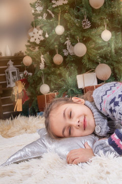 Child girl sleeping dream with happy emotions under Christmas decoration