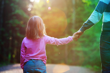 Mother holding hand of little daughter in nature
