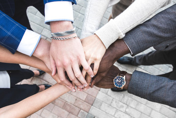 business, people and teamwork concept - smiling group of businesspeople standing in circle and putting hands on top of each other