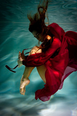 Woman under the water in a red dress. - obrazy, fototapety, plakaty