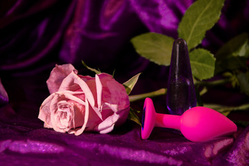 Silicone dildo Sex toy and a pink rose on a dark background.