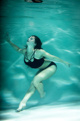 Woman under the water in a black clothes.