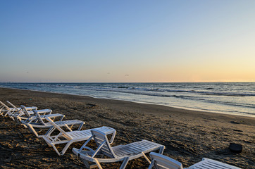 Sunbeds on the beach of Black Sea at sunrise, warm sunshine atmosphere